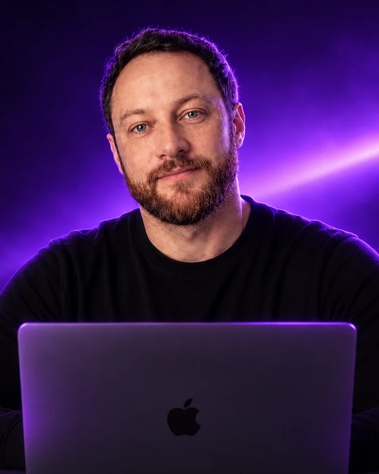 César Kolokovski trabalhando no notebook, com iluminação e reflexos roxos